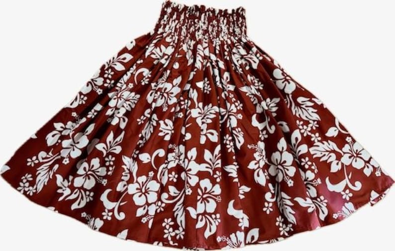 Op de afbeelding: Een bruine rok met een wit bloemenpatroon. De rok heeft een gerimpelde tailleband en een volle vorm. Het bloemmotief omvat hibiscusbloemen en bladeren, wat een tropische uitstraling cre&euml;ert. Perfect voor de zomer.