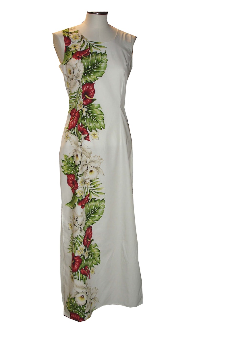 Puede incluir: Un vestido blanco maxi sin mangas con estampado floral de flores rojas, blancas y verdes. El estampado floral est&aacute; en el lado izquierdo del vestido.