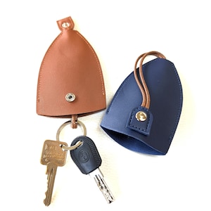 May include: Two keychains, one brown and one blue, with a key ring and two keys attached. The keychains are made of leather and have a snap closure.