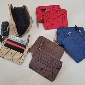 May include: Five zippered wallets with geometric patterns. The wallets are in beige, red, brown, and blue. Each wallet has a zipper closure and multiple card slots.