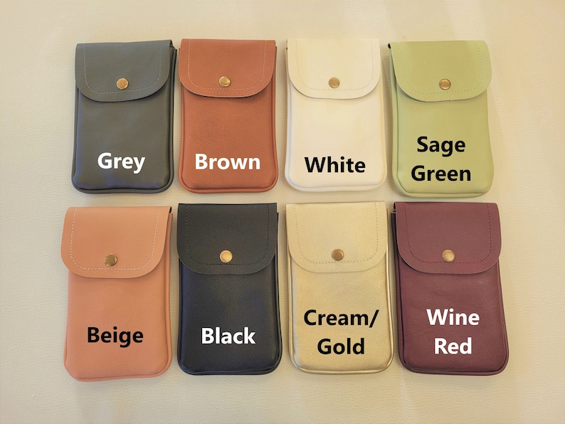 May include: Eight different colored phone pouches with a flap and a button closure. The pouches are arranged in two rows of four. The colors are grey, brown, white, sage green, beige, black, cream/gold, and wine red.