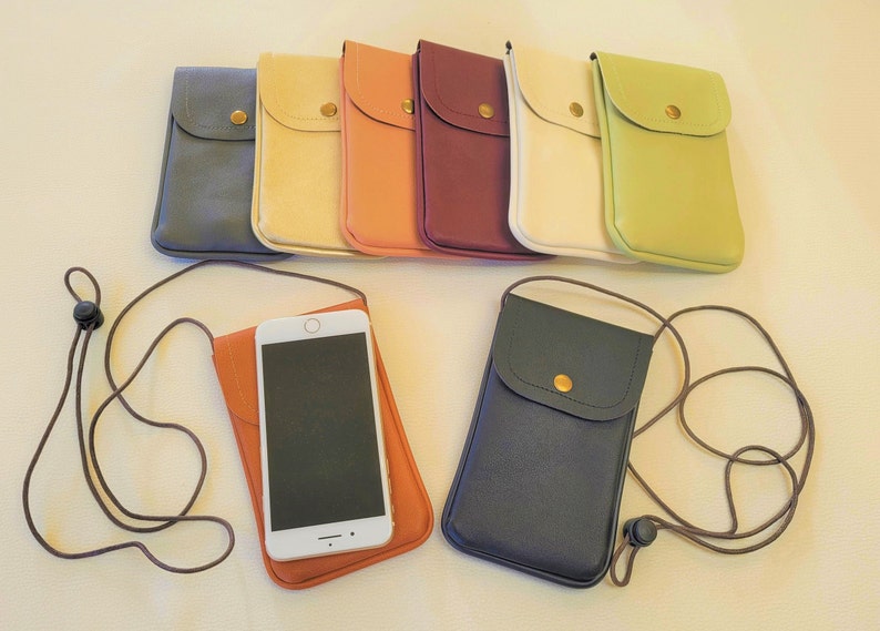 May include: Assortment of nine phone pouches in various colors, including blue, beige, orange, red, white, and green. Each pouch has a small pocket on the front and comes with a brown adjustable strap.