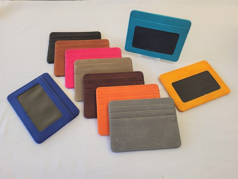 May include: Assortment of ten leather card holders in various colors, including blue, orange, brown, gray, pink, and turquoise. Each card holder has a clear plastic window for displaying identification.