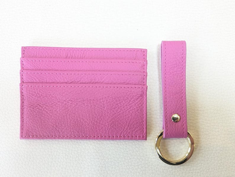 May include: A pink leather card holder with six card slots and a matching pink leather key chain with a gold ring.
