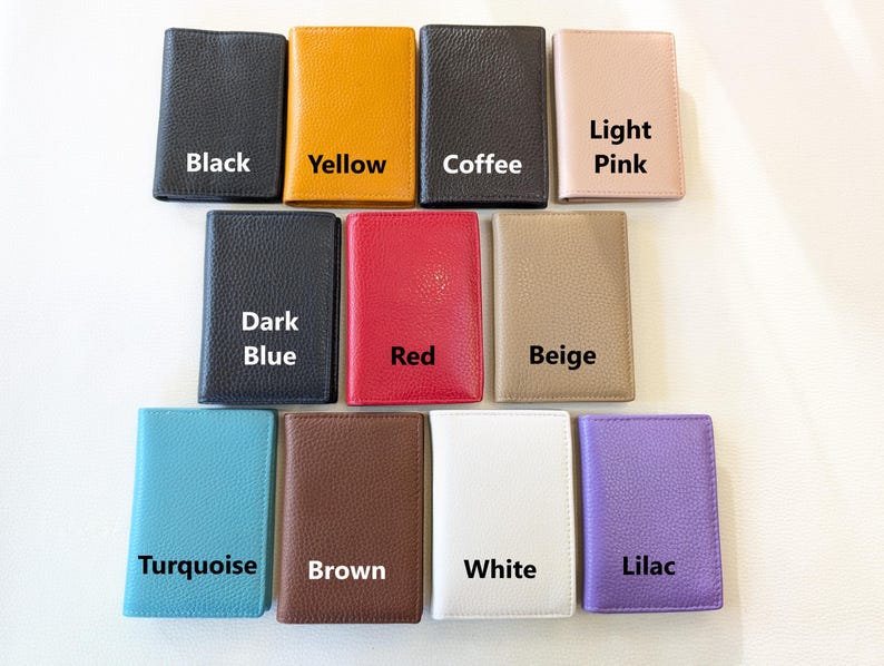 May include: A collection of leather wallets in various colors, including black, yellow, coffee, light pink, dark blue, red, beige, turquoise, brown, white, and lilac. Each wallet is labeled with its respective color.
