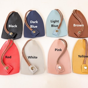 May include: Eight leather keychains in different colors, including black, dark blue, light blue, brown, red, white, pink, and yellow. Each keychain has a loop for attaching keys and a small metal tag with the color name printed on it.