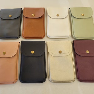 May include: Eight different colored phone cases with a small flap and a gold button. The cases are made of a soft, textured material.