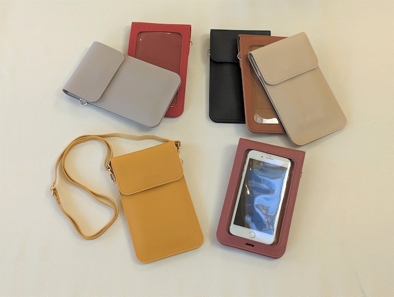 May include: Assortment of phone cases in various colors, including gray, brown, yellow, and red. Some cases have a clear plastic window for viewing the phone screen. One case has a strap for carrying over the shoulder.