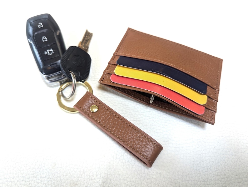 May include: A brown leather wallet with a key ring attached. The wallet has three credit cards inside. The key ring has a car key and a small metal key.