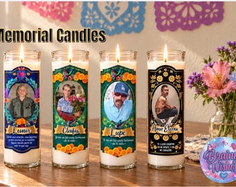 May include: Four cylindrical glass memorial candles with white wax and lit wicks. Each candle features a unique label with a portrait, a name, and Spanish text. The labels include Leonor, Cleofas, Lupe, and Amor Eterno with floral and hummingbird designs.