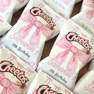 May include: Several white Cheetos snack bags with pink bows and the text "Samarah's 11th Birthday". The Cheetos logo is visible on the bags. The bags are arranged on a wooden surface.