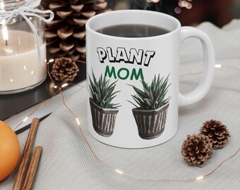 May include: White ceramic mug with a green and black graphic of two potted plants and the text "PLANT MOM".