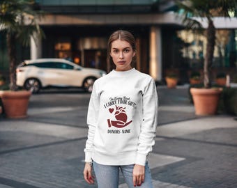 May include: White sweatshirt with a red heart and the text "In Every Beat, I Carry Your Gift. Donors Name".