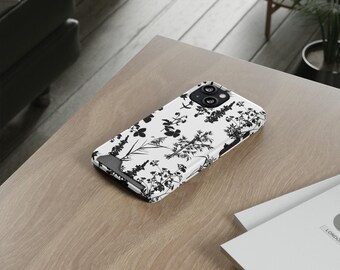 May include: A white phone case with a black floral pattern. The case has a camera lens cutout and a raised edge around the screen.