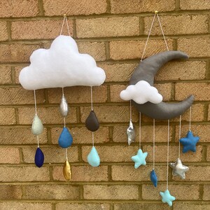 May include: A white felt cloud with raindrops hanging from it in shades of blue, silver, and gold. A grey felt crescent moon with white felt clouds and blue felt stars hanging from it.