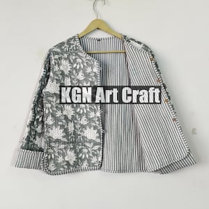 Può includere: Una giacca reversibile con una stampa floreale su un lato e un motivo a righe sull'altro. La giacca è appesa a un appendiabiti contro un muro bianco. Il testo "KGN Art Craft" è visibile sulla giacca.