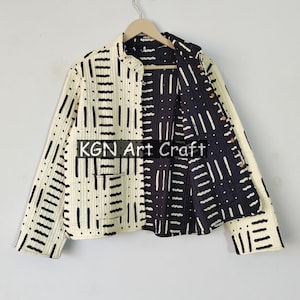 Puede incluir: Una chaqueta reversible con un patrón geométrico en blanco y negro. La chaqueta tiene un cuello mandarín y mangas largas. El texto "KGN Art Craft" es visible en la chaqueta.