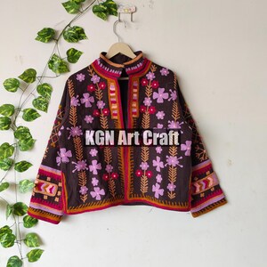 Puede incluir: Una chaqueta marr&oacute;n bordada con dise&ntilde;os florales de color rosa y rojo. La chaqueta tiene un cuello alto y mangas largas. El texto "KGN Art Craft" es visible en la parte delantera de la chaqueta.