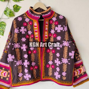 Puede incluir: Una chaqueta marr&oacute;n bordada con dise&ntilde;os florales rosas y naranjas. La chaqueta tiene un cuello alto y una cremallera. El texto "KGN Art Craft" est&aacute; bordado en la parte delantera de la chaqueta.