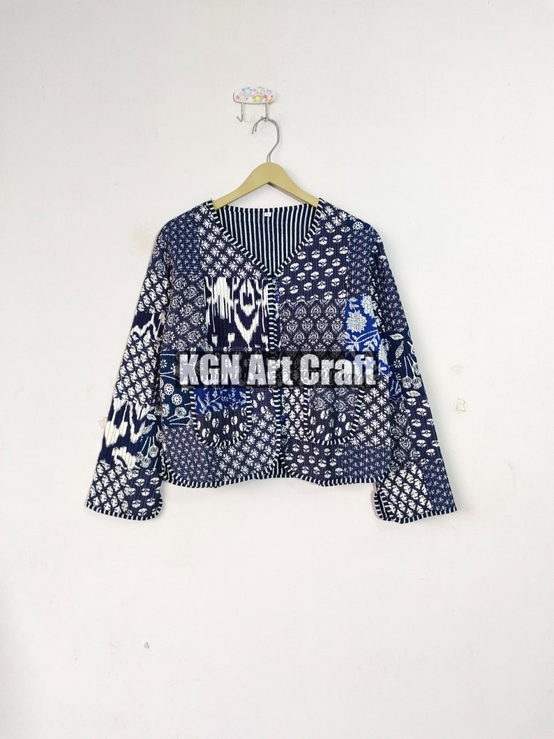 May include: A blue and white patchwork jacket with a V-neck and long sleeves. The jacket has a variety of patterns, including floral, geometric, and paisley. The text "KGN Art Craft" is printed on the front of the jacket.