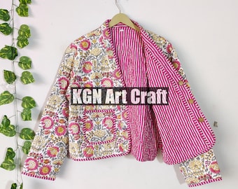 May include: A pink and white quilted jacket with floral print and striped fabric. The jacket has a button closure and a pocket on the front. The text "KGN Art Craft" is printed on the jacket.
