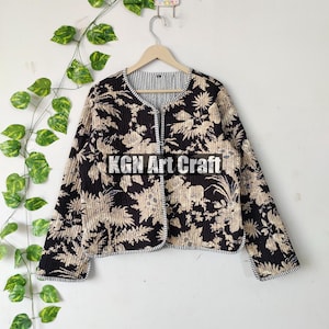 May include: A black and cream floral print quilted jacket with a black and white striped lining. The jacket has a button closure and long sleeves. The text "KGN Art Craft" is visible on the front of the jacket.