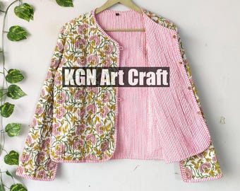 May include: A pink and white quilted jacket with a floral print on one side and pink and white stripes on the other side. The jacket has a button closure and long sleeves. The text "KGN Art Craft" is printed on the front of the jacket.