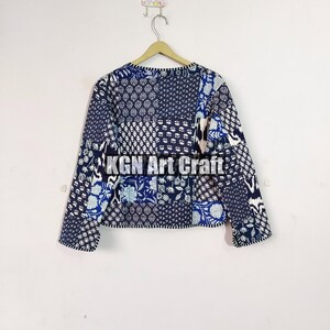 May include: A blue and white patchwork quilted jacket with a floral pattern. The jacket has long sleeves and a round neckline.