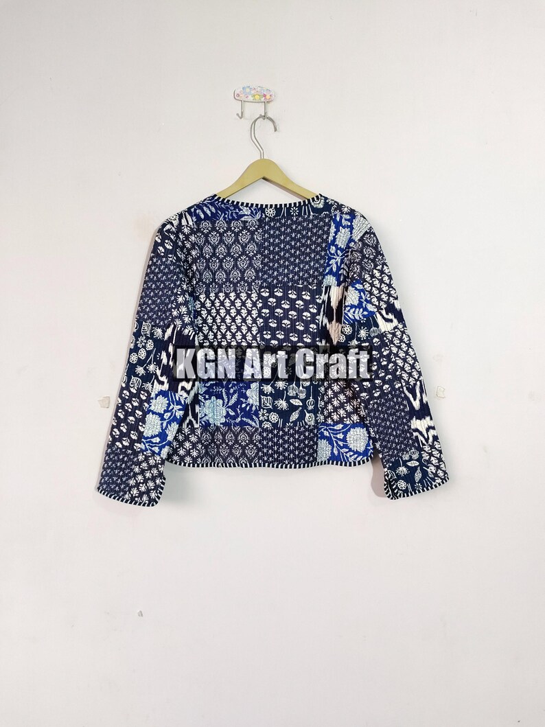 May include: A blue and white patchwork quilted jacket with a floral pattern. The jacket has long sleeves and a round neckline.