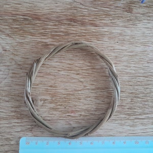 May include: A natural woven wreath made from thin twigs, approximately 6 inches in diameter, on a wooden surface.