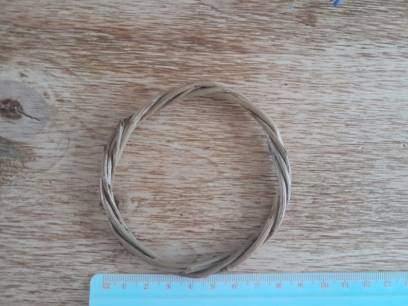 May include: A natural woven wreath made from thin twigs, approximately 6 inches in diameter, on a wooden surface.