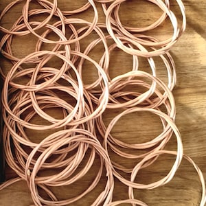 May include: A pile of woven wicker rings, likely used for crafts or home decor. The rings are light brown and have a natural, rustic look.