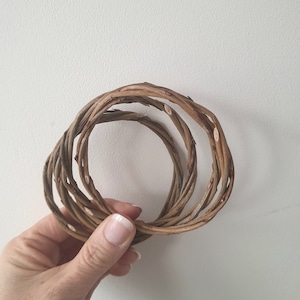 May include: A set of three brown woven rings made from natural twigs.