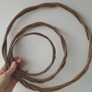 May include: Three brown willow wreaths of varying sizes, woven together in a circular shape.