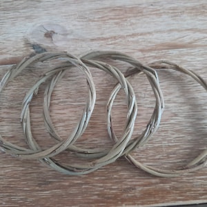 May include: Four woven willow rings, each with a natural brown color, are stacked on top of each other. The rings are made of thin, flexible branches that have been woven together to create a circular shape.