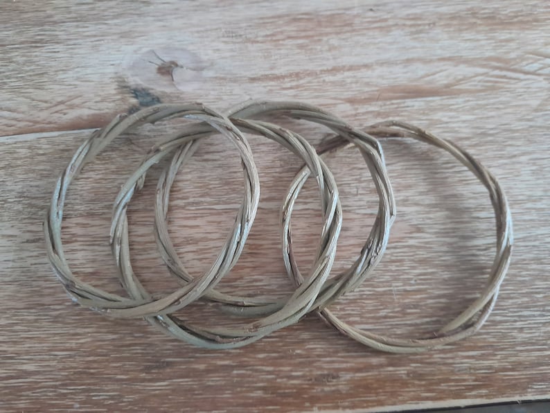 May include: Four woven willow rings, each with a natural brown color, are stacked on top of each other. The rings are made of thin, flexible branches that have been woven together to create a circular shape.