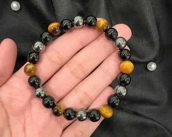 May include: A bracelet made of tiger's eye, black onyx, and hematite beads. The bracelet is brown, black, and silver.