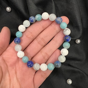 May include: A bracelet made of white, blue, and light blue round beads. The bracelet is made of natural stones.