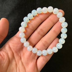K&ouml;nnte beinhalten: Ein wei&szlig;es Opal-Perlenarmband mit durchscheinendem, irisierendem Finish. Das Armband besteht aus runden Perlen und ist etwa 18 cm lang.