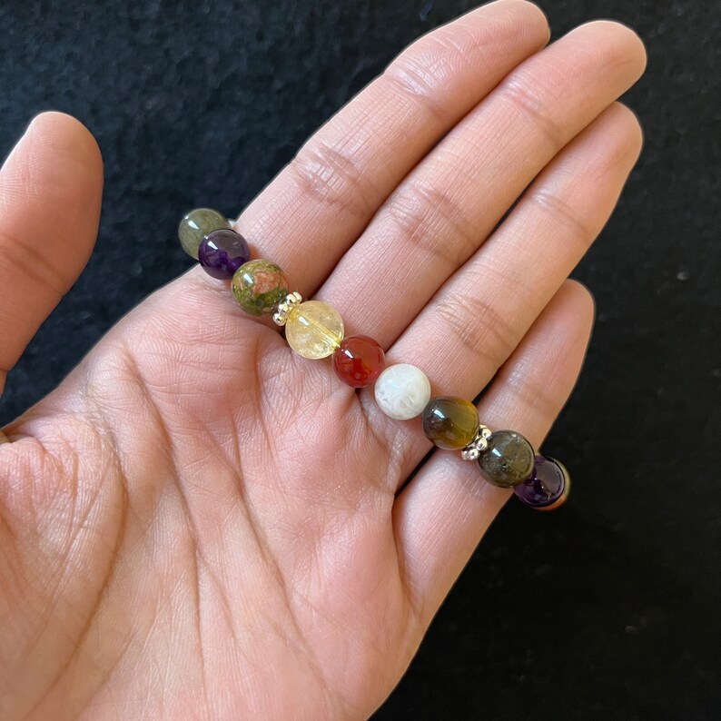May include: A multi-colored beaded bracelet with a variety of stones, including amethyst, green aventurine, citrine, carnelian, moonstone, tiger's eye, and black obsidian.