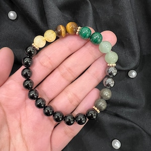 May include: A black, green and gold beaded bracelet with gold spacers. The bracelet is made of various gemstones, including black onyx, green aventurine and tiger's eye.
