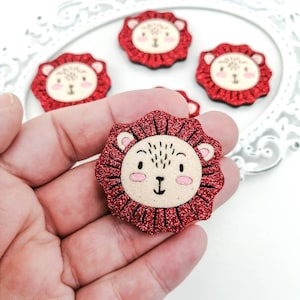 May include: Red glitter lion head with a white face and black eyes. The lion head is a craft supply for making hair bows, headbands, or other crafts.