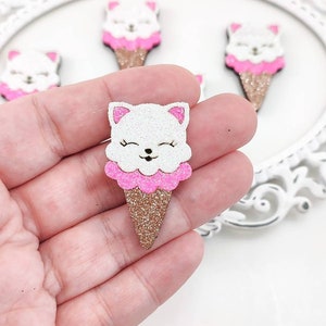 May include: A white glitter cat ice cream cone with pink glitter ice cream and a gold glitter cone.