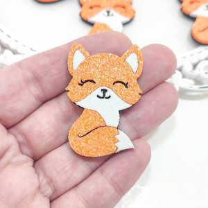 Può includere: Abbellimenti a forma di volpe glitterata arancione con dettagli bianchi e contorni neri. La volpe ha un volto sorridente con gli occhi chiusi. Questi abbellimenti decorativi sono ideali per l'artigianato e i progetti fai-da-te.