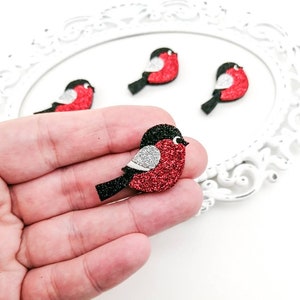 May include: Four red glitter bird ornaments with black wings and white accents. The birds are approximately 2 inches in size.