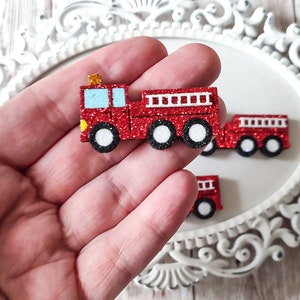 May include: Red glitter fire engine with black wheels and a yellow ladder. The engine is made of felt and is about 2 inches long.