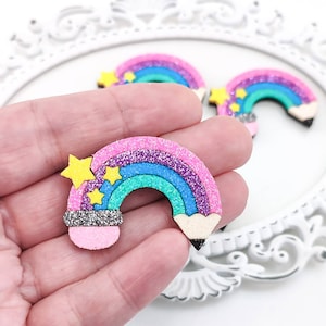 Könnte beinhalten: Ein regenbogenfarbener Bleistift in Form eines Handwerks mit Glitzer und gelben Sternen. Der Bleistift ist rosa, lila, blau, grün und schwarz.