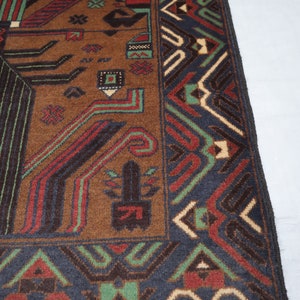 May include: Close-up of a brown, black, green and cream patterned rug with fringe. The rug has a geometric design with intricate details.