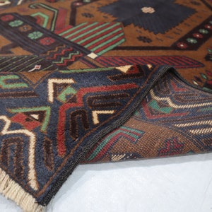 May include: A brown, blue, green and red patterned rug with fringe. The rug is folded in half, showing the pattern on both sides.