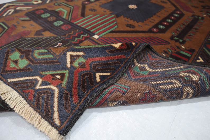 May include: A brown, blue, green and red patterned rug with fringe. The rug is folded in half, showing the pattern on both sides.